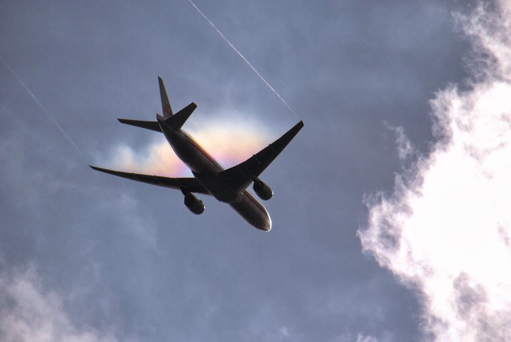 An American Airlines plane cutting through thin cloud and creating a vapour trail after taking off from Heathrow. by Christopher Hood