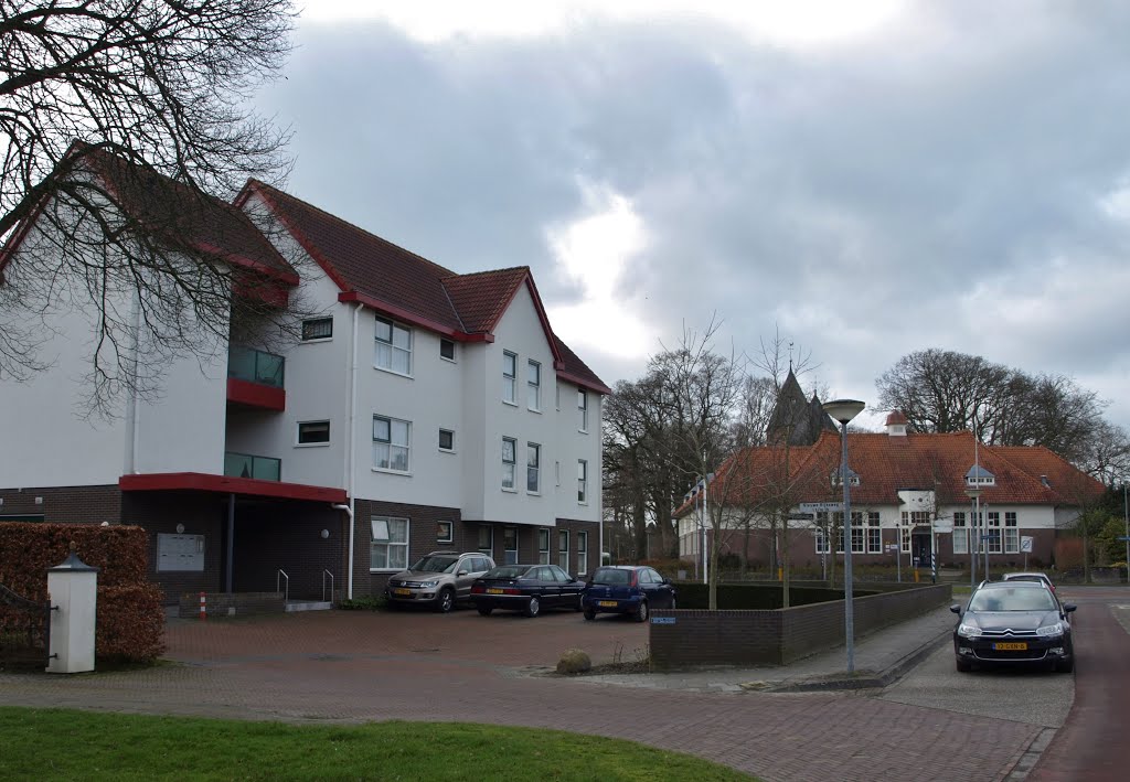 Links het appartementencomplex aan de Nieuwe Rijksweg 1 t/m 1h in Vries, op de locatie van het Café Restaurant "Quatre Bras" annex slijterij van Henderikus Pranger, later van Ubel Tolner. De architect is Emile Koopmans van Team 4 Architecten in Groningen. Op de achtergrond het Dorpshuis "De Pan", voorheen de Openbare Lagere School (1915), van architect is Yvo Dirk Havermans, geb. Gorinchem 3-9-1888, ovl. Den Haag 22-1-1945. De woning van het hoofd van de school op nummer 6 is ook van Havermans. by Hans R van der Woude