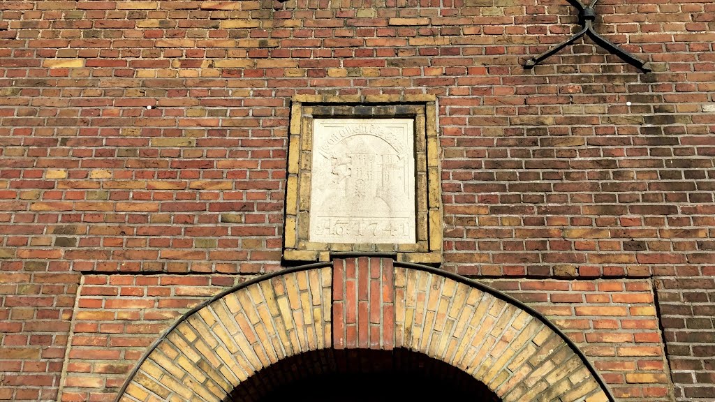 Gott allein die Ehre , Inschrift der Tafel verziert auf einem Banner ( Anno 1741 ) am Portal der St. Johannis Kirche in Flensburg . Darin zwei Löwen einen Hügel auf dem sich ein Turm erhebt . by www.fleno.de