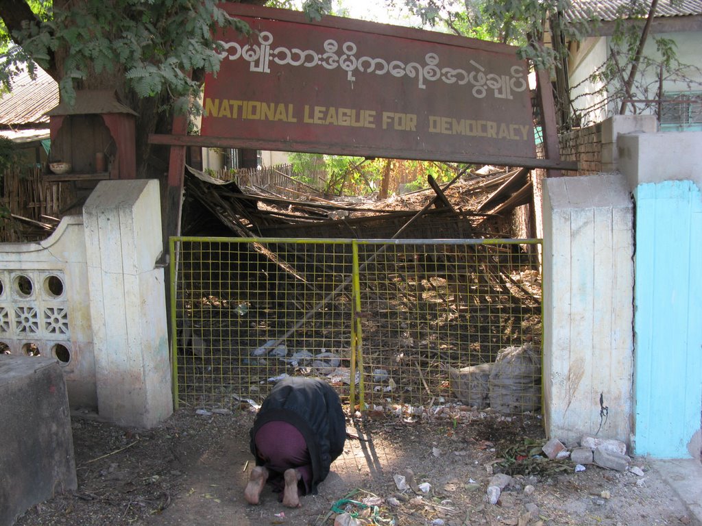 A man pry in front of the house of league of democraty, it was destroyed by army. by jean-claude Baïsse