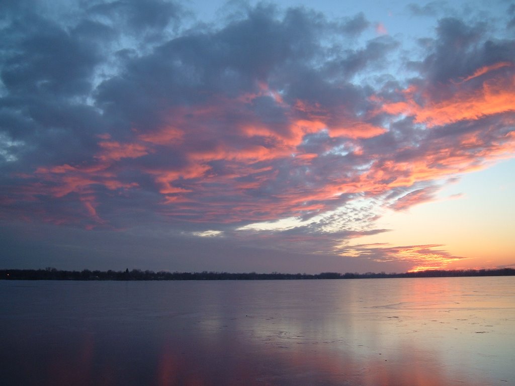 Dec 2004 - Worthington, Minnesota. Winter sunset clouds reflecting on the frozen Lake Okabena. by BRIAN ZINNEL