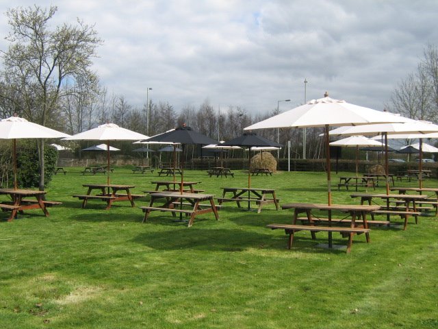 The sets of wooden picnic tables and big white parasols, outside on the grass by Robert'sGoogleEarthPictures