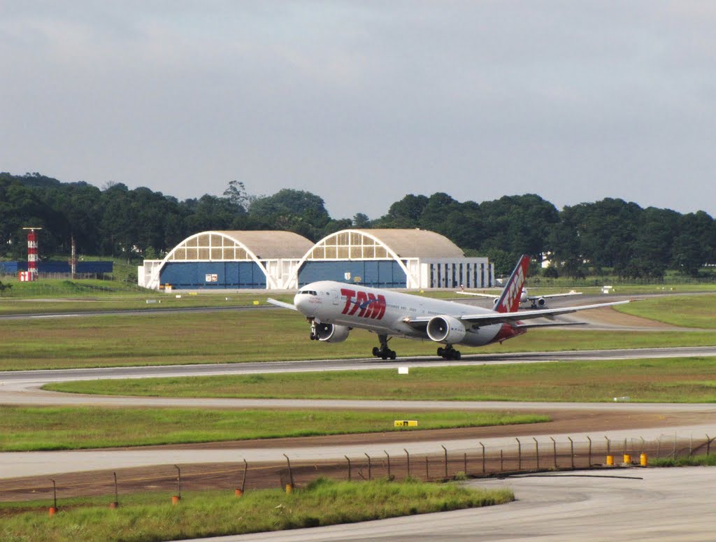 Hangares (BASP) & decolagem (JJ 77W / PT-MUC - voo GRU-SCL) - vista desde o "morrinho" (spotter point) - São Paulo-Guarulhos (GRU), SP, Brasil. by André Bonacin