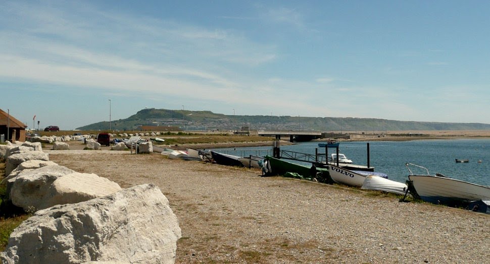 Boats in front of Chesil Beach Holiday Village with Ferry Bridge behind by griffmonster