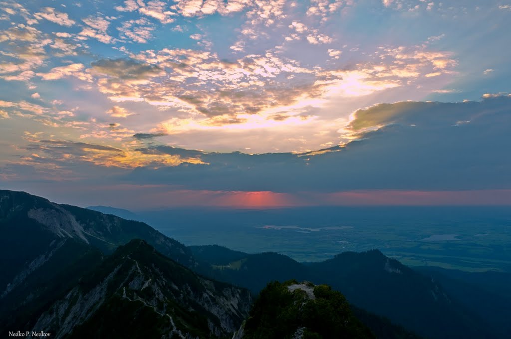 Sonnenuntergang am Herzogstand in Oberbayern mit dem Heimgarten-Gipfelkreuz und dem Staffelsee by nedkovn