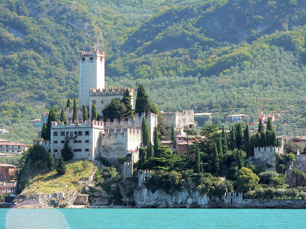 Italy: Gardalake - Limone, with a speedboat on the lake, view of Malcesine, the Scaligero Castle by Yory