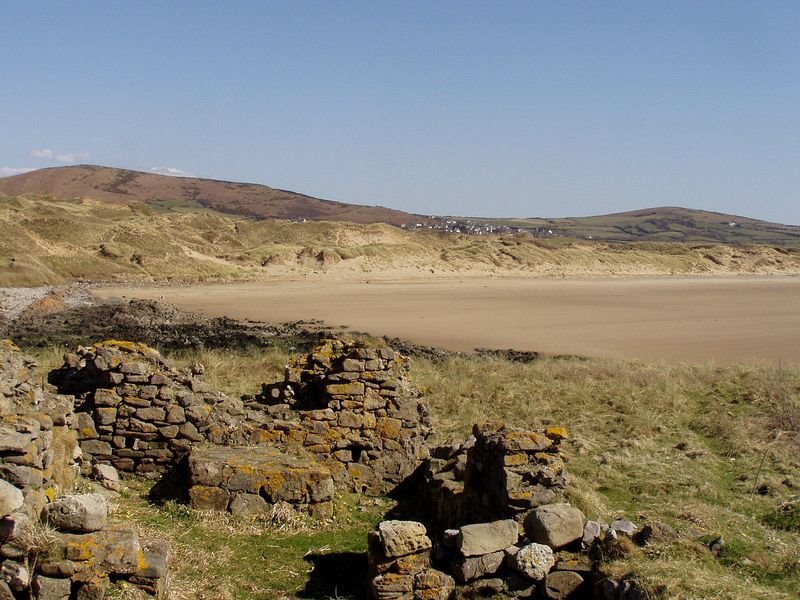 Ancient Monastic ruins on Burry Holmes Island with sand dunes of Llangenydd Beach in background by Stephen John