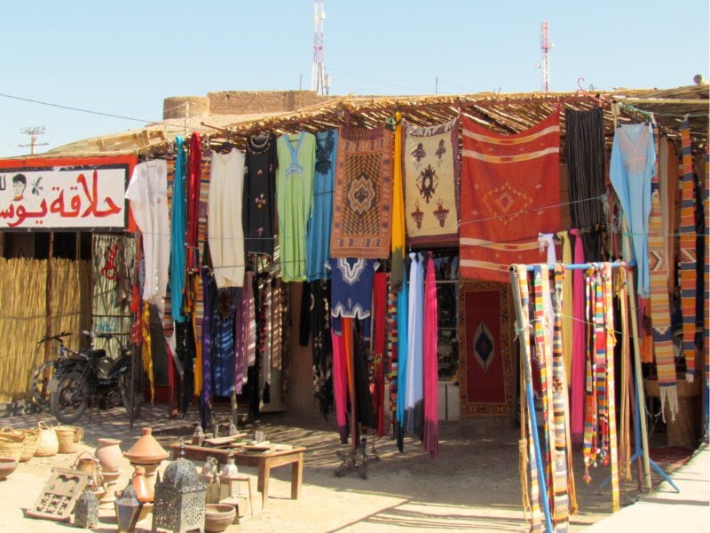 Agdz. Market: clothes & souvenirs. Morocco. Agdz is located about 65 km south of Ouarzazate, 92 km north of Zagora. Agdz which means "resting place" is located on the old caravan route linking Marrakech to Timbuktu. by Linda De Volder