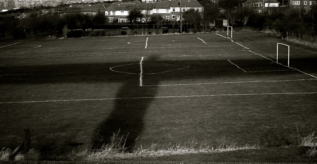 Angel of the North casting its shadow symmetrically over a football pitch by heandfi