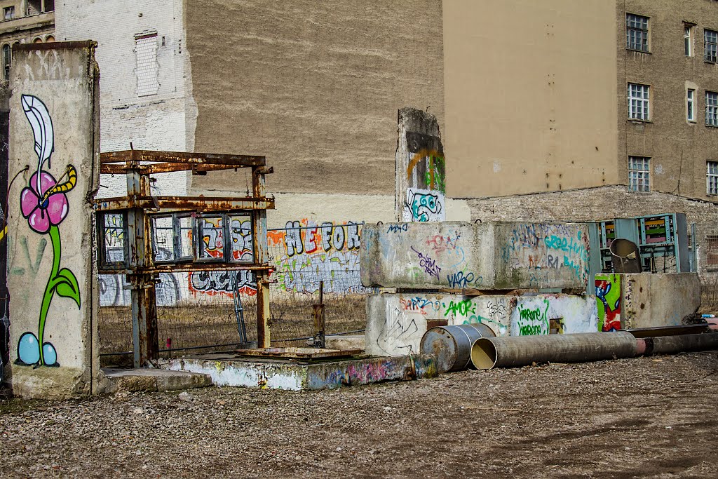 Rotting pieces of the berlin wall with watchtower by lucia copa