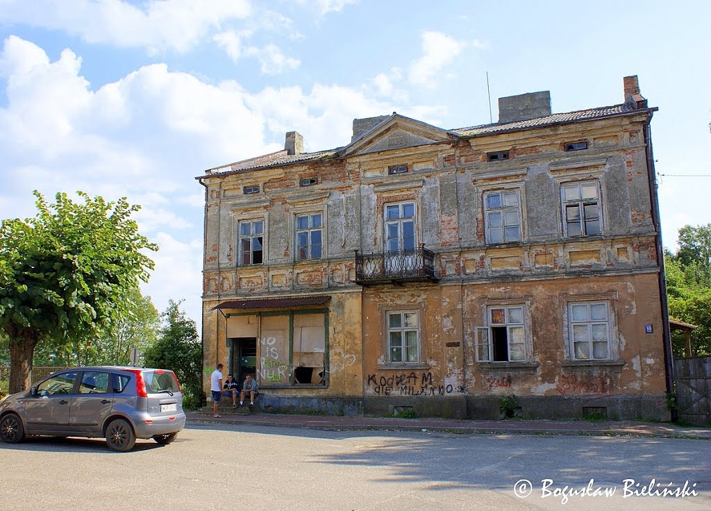 Jedną z najstarszych budowli miejskich w Nowym Mieście nad Pilicą, jest neoklasycystyczna kamienica, murowana z 1898 r. przy pl. Honorata Koźmińskiego 10. Zrealizowany dom jest obiektem założonym na rzucie prostokąta, jednopiętrowym, pięcioosiowym, z jedn by Boguslaw2