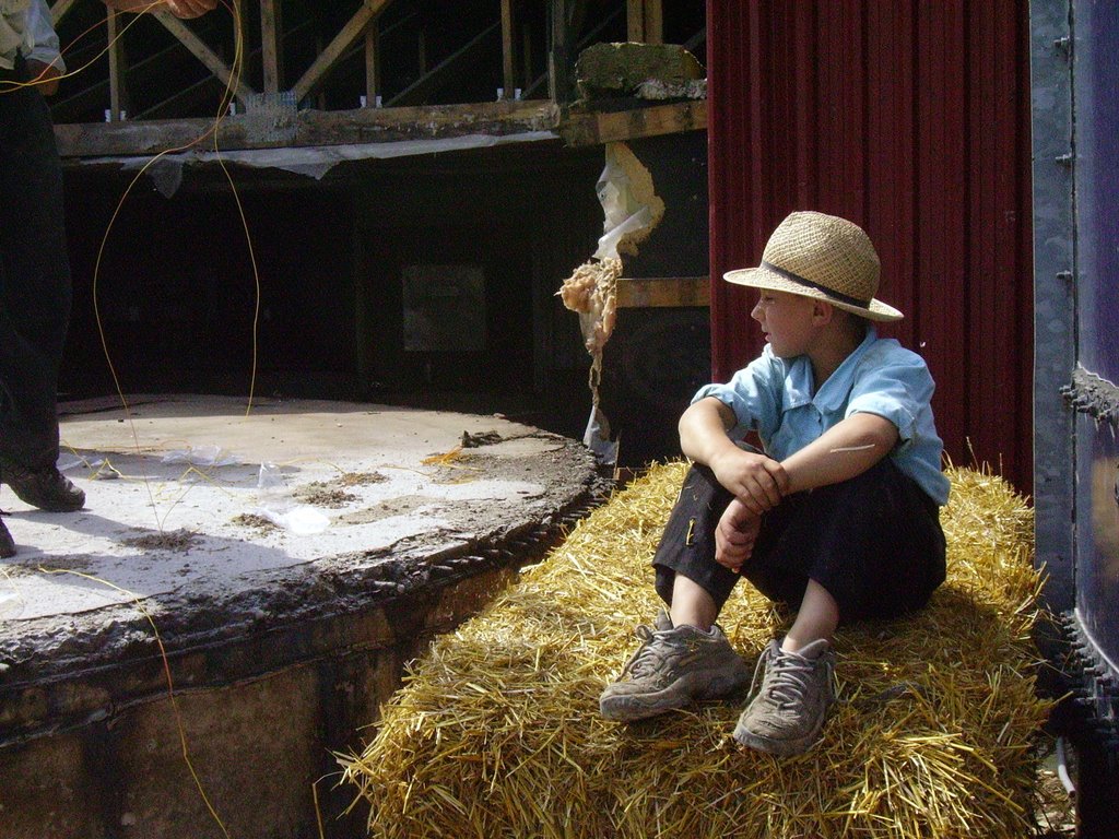 Milverton - mennonite boy at a farm looking at working mennonites by Maarten Groenbroek