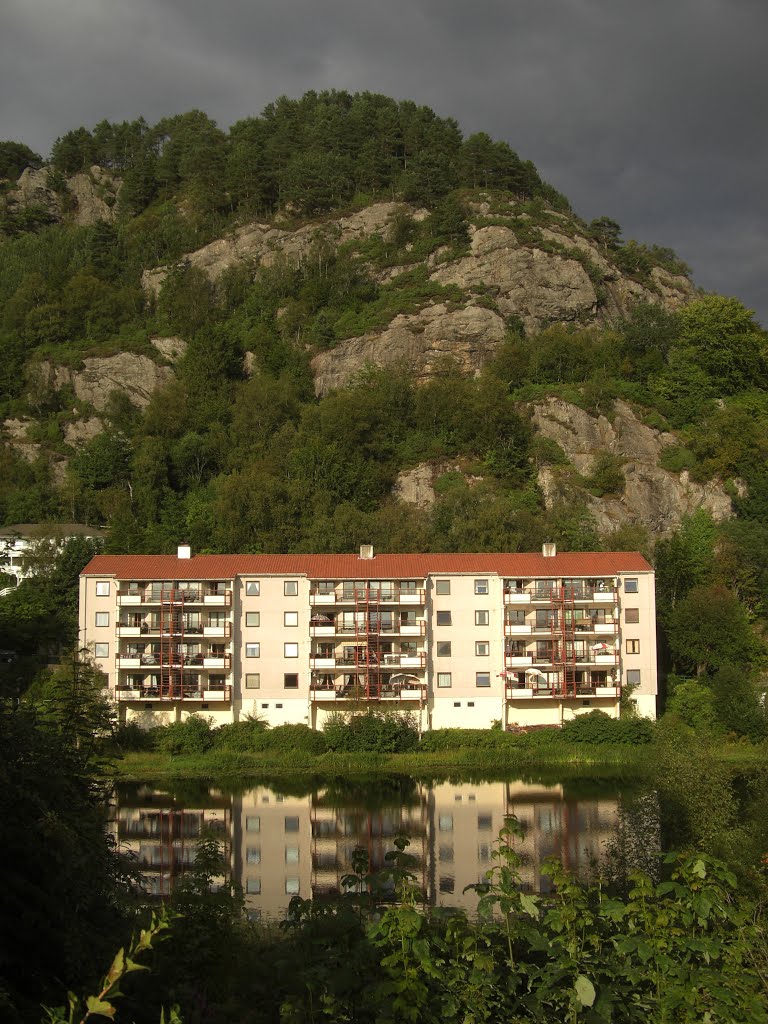 Sunshine, very dark grey clouds, a block house and nice reflections by Mona Lygre